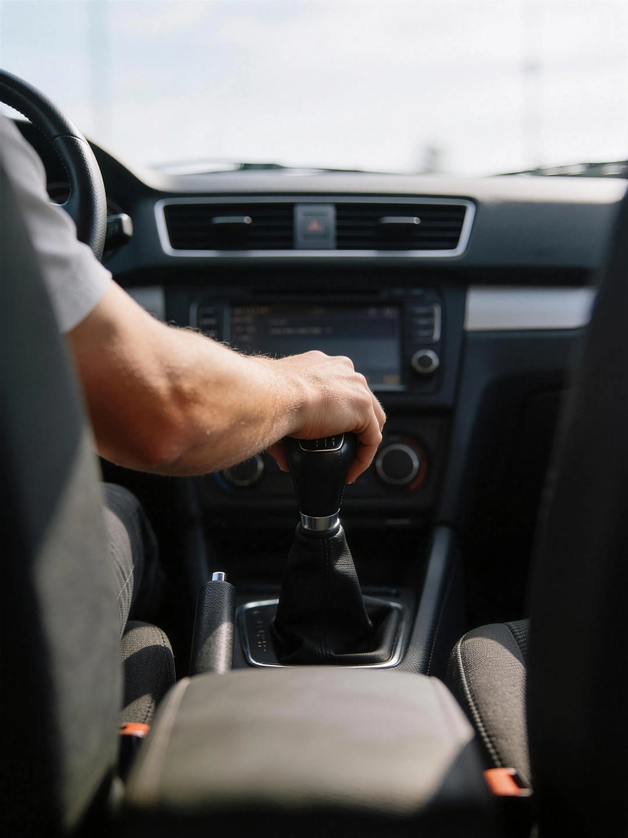 Hand op de versnellingspook tijdens een rijles